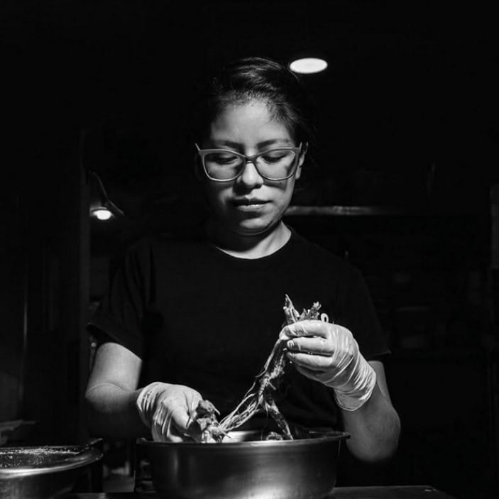 a woman is preparing food in a metal bowl