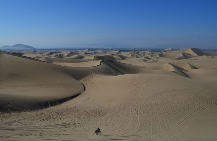 A man with a child doing sandboarding in the sand dunes of Ica
